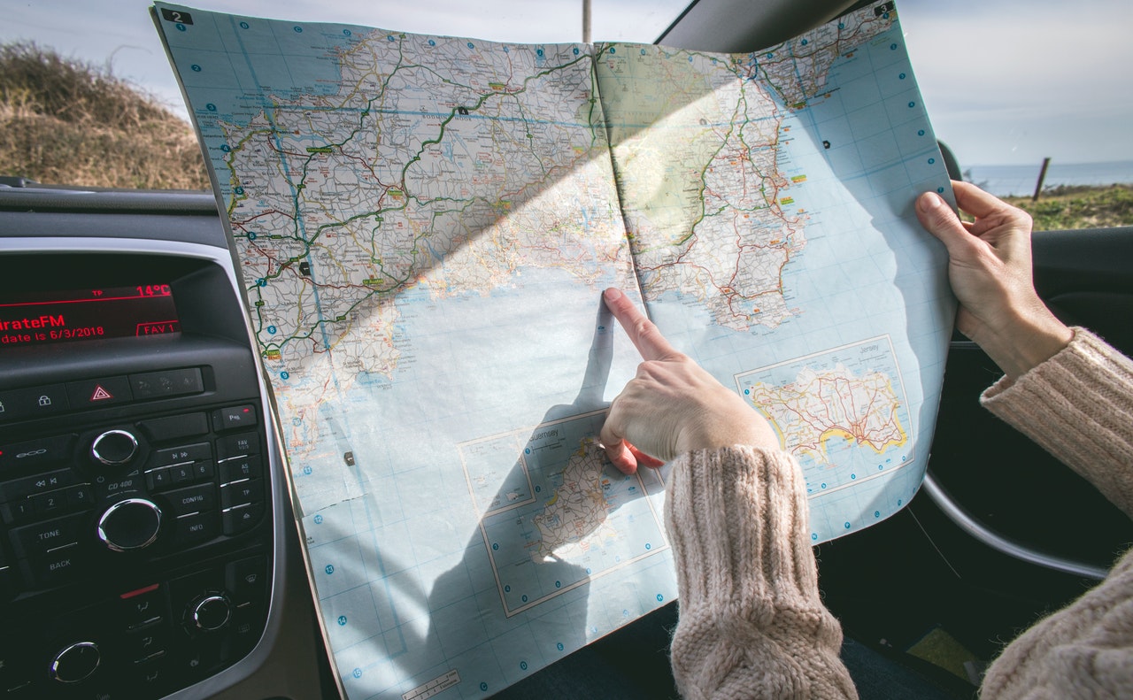 Person in a car with a roadmap pointing to their route.. 